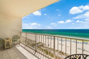 Un balcon donnant sur la plage, avec une balustrade et deux chaises.