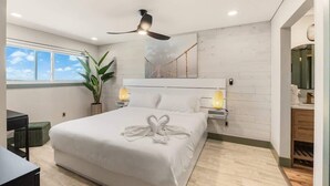 Une chambre moderne avec un grand lit, un ventilateur de plafond, des lampes de chevet et une vue sur le ciel par une fenêtre.