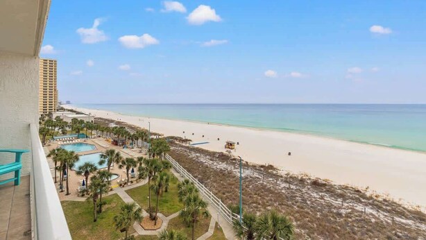 Ein Strandhotel mit Pool, Palmen und Blick auf Strand und Meer.
