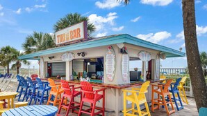 Eine Tiki-Bar mit bunten Stühlen und Tischen, einem Schild und einer Speisekarte.