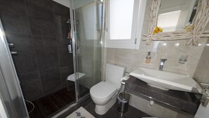 Ein modernes Badezimmer mit einer gläsernen Duschkabine, einer weißen Toilette und einem Waschbecken mit Marmorplatte.