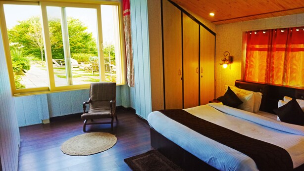 A bedroom with a large bed, a chair, a window, and a view of the outdoors.