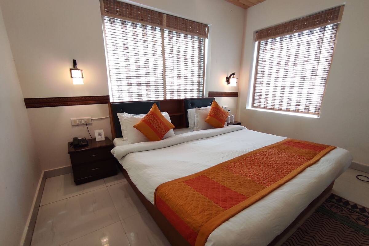 A hotel room with a large bed, two bedside tables, a nightstand, and a wall-mounted telephone.