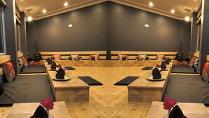 A mirrored room with a central table, benches, and a ceiling with recessed lighting.