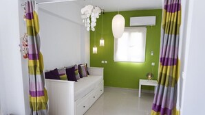 Ein modernes Schlafzimmer mit einer weißen Couch, grünen Wänden und einer weißen Klimaanlage.