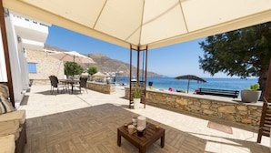Eine Terrasse mit Holzboden, einem Tisch mit Kerzen und Blick auf das Meer und die Berge.