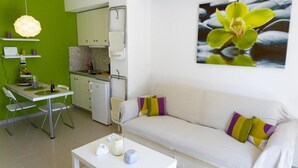 Ein modernes Wohnzimmer mit einem weißen Sofa, einem Esstisch und einer Küchenzeile.