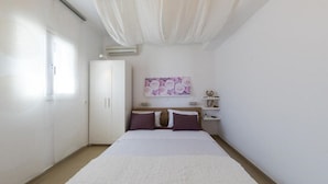 Ein Schlafzimmer mit Bett, Kleiderschrank, Nachttisch und Wandklimaanlage.