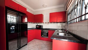 Una cocina con armarios rojos, un refrigerador negro, una estufa y un lavamanos.