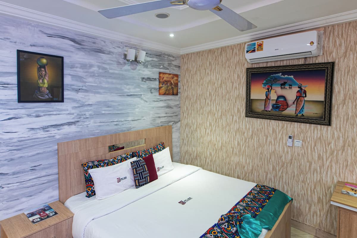 Une chambre à coucher avec un lit en bois, un ventilateur de plafond, un climatiseur fixé au mur et un tapis à motifs.