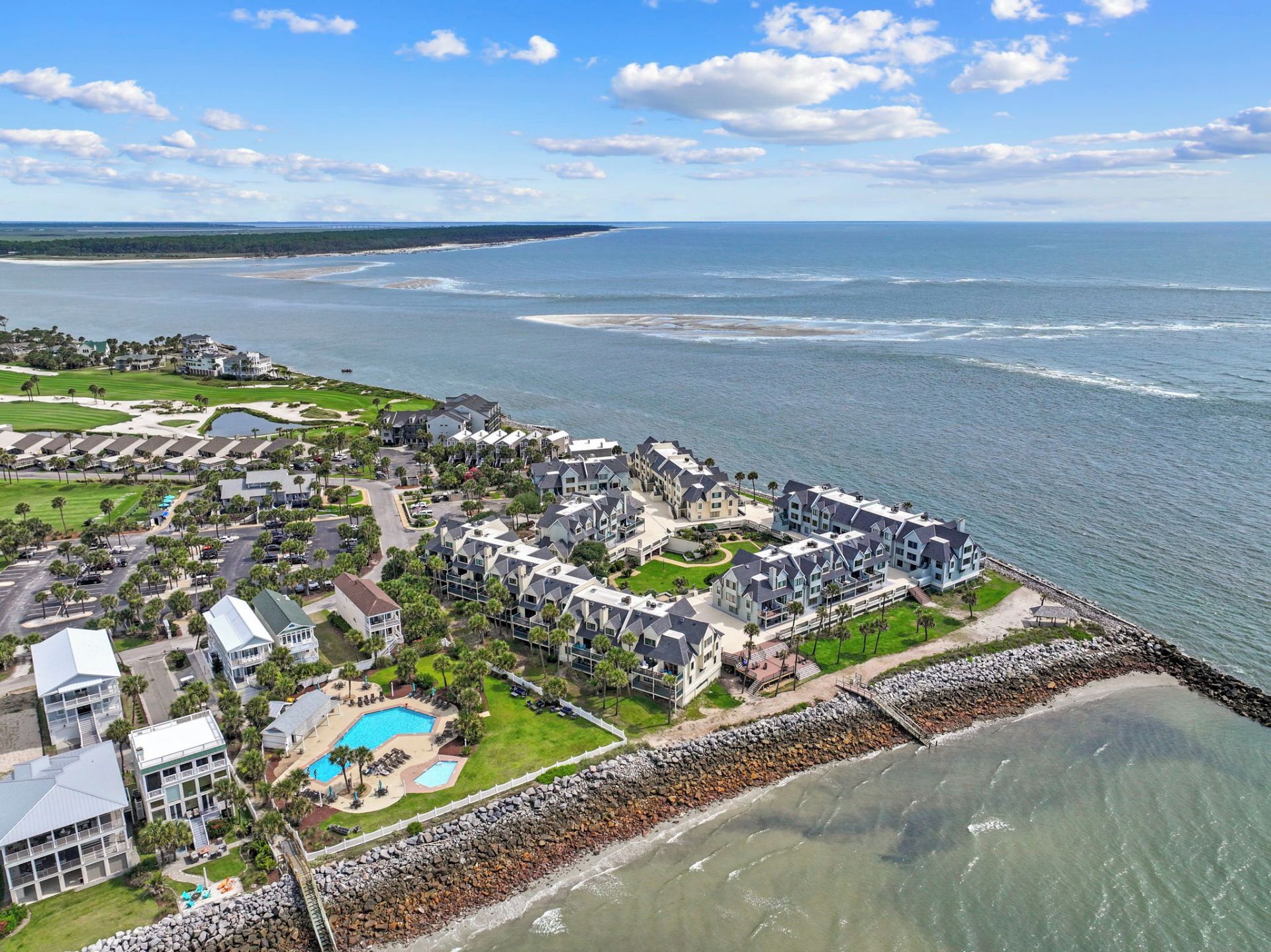 A coastal resort with multiple buildings, a swimming pool, and a rocky shoreline.