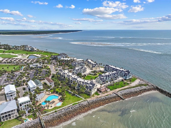 A coastal resort with multiple buildings, a swimming pool, and a rocky shoreline.
