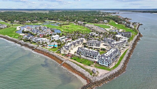 Ein Luftbild eines Küstenresorts mit mehreren Gebäuden, einem Golfplatz und einem Yachthafen.