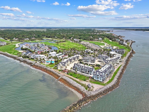 An aerial view of a coastal resort with multiple buildings, a golf course, and a marina.