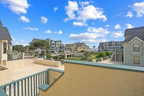 A coastal residential area with multiple two-story houses, a swimming pool, and a clear view of the ocean.