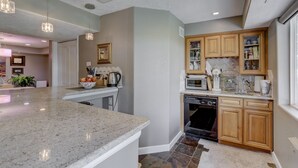 A modern kitchen with granite countertops, wooden cabinets, and built-in appliances. - Colorado Greenbelt Vacation Home (Erie)