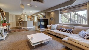 A modern living room with a fireplace, a sofa, a coffee table, and a staircase leading to an upper level. - Colorado Greenbelt Vacation Home (Erie)