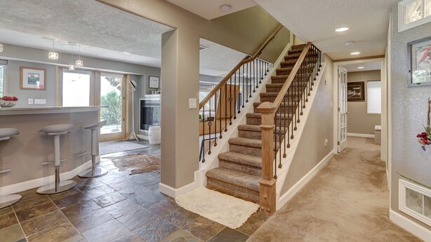 A home interior with a staircase, kitchen area, and bar stools. - Colorado Greenbelt Vacation Home (Erie)