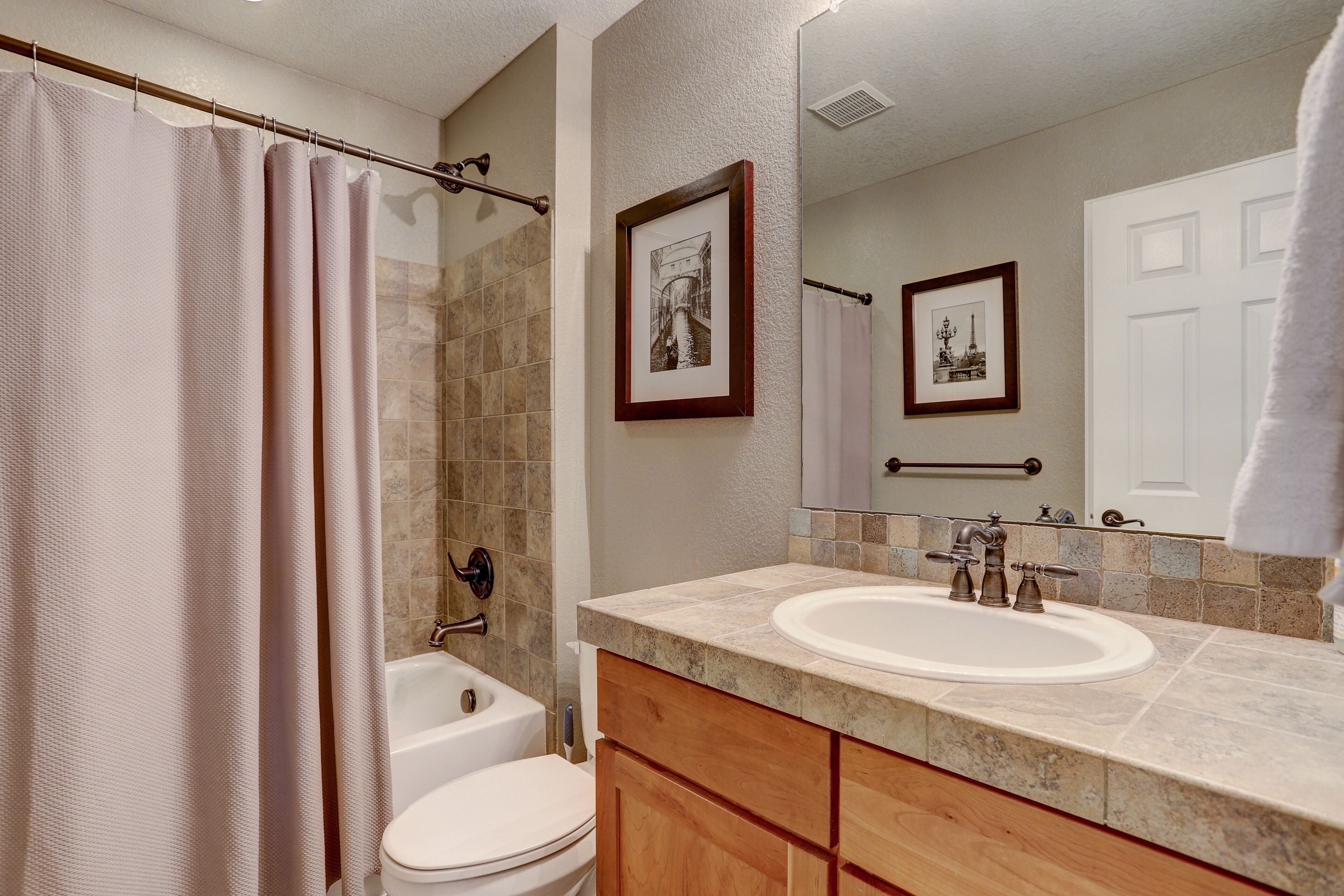 A bathroom with a bathtub, toilet, sink, and vanity.