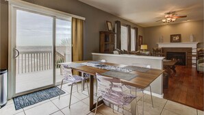 A dining area with a view of the beach, a fireplace, and a ceiling fan. - Colorado Greenbelt Vacation Home (Erie)