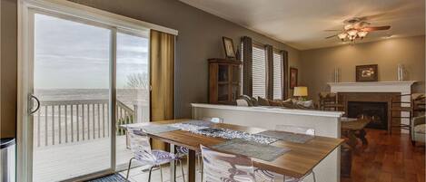 A dining area with a view of the beach, a fireplace, and a ceiling fan.