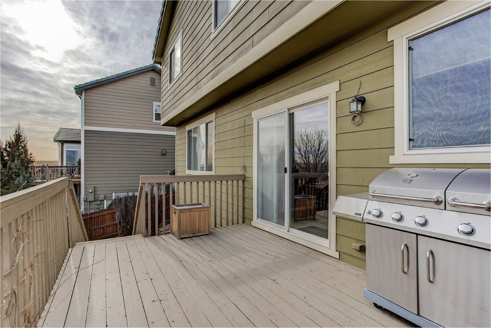 A deck with a grill and sliding glass doors.