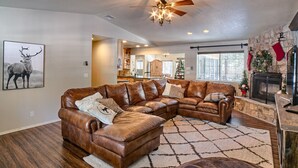 A spacious living room with a large sectional sofa, a fireplace, and a ceiling fan. - Perfect Pinetop Getaway; 2 Master Suites; Wifi, Satellite; Hot tub, Dog Friendly (Pinetop)
