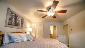 A bedroom with a bed, a ceiling fan, a framed picture on the wall, and two doors leading to other rooms. - Perfect Pinetop Getaway; 2 Master Suites; Wifi, Satellite; Hot tub, Dog Friendly (Pinetop)