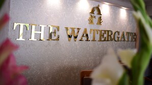 Une enseigne avec l’inscription « THE WATERGATE » en lettres dorées sur un mur à texture.