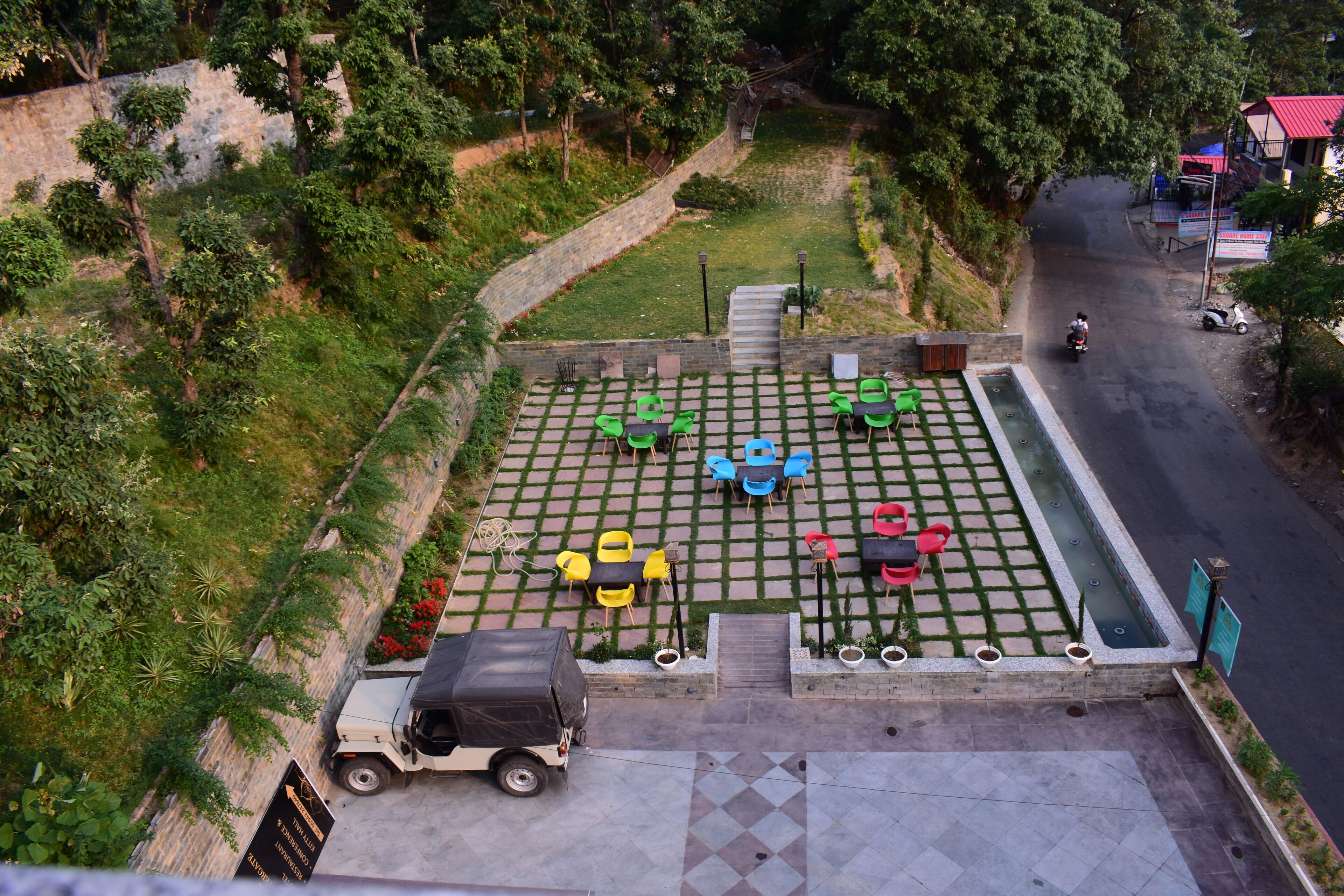 An outdoor seating area with tables and chairs, a paved walkway, and a vehicle parked nearby.