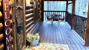 Eine Holzhütte mit freundlicher Schilder, einer Veranda und einem Tisch mit Stühlen.