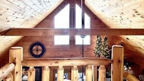 Ein Holzinnenraum mit schrägverdeckter Decke, einer Uhr und einem Weihnachtsbaum.