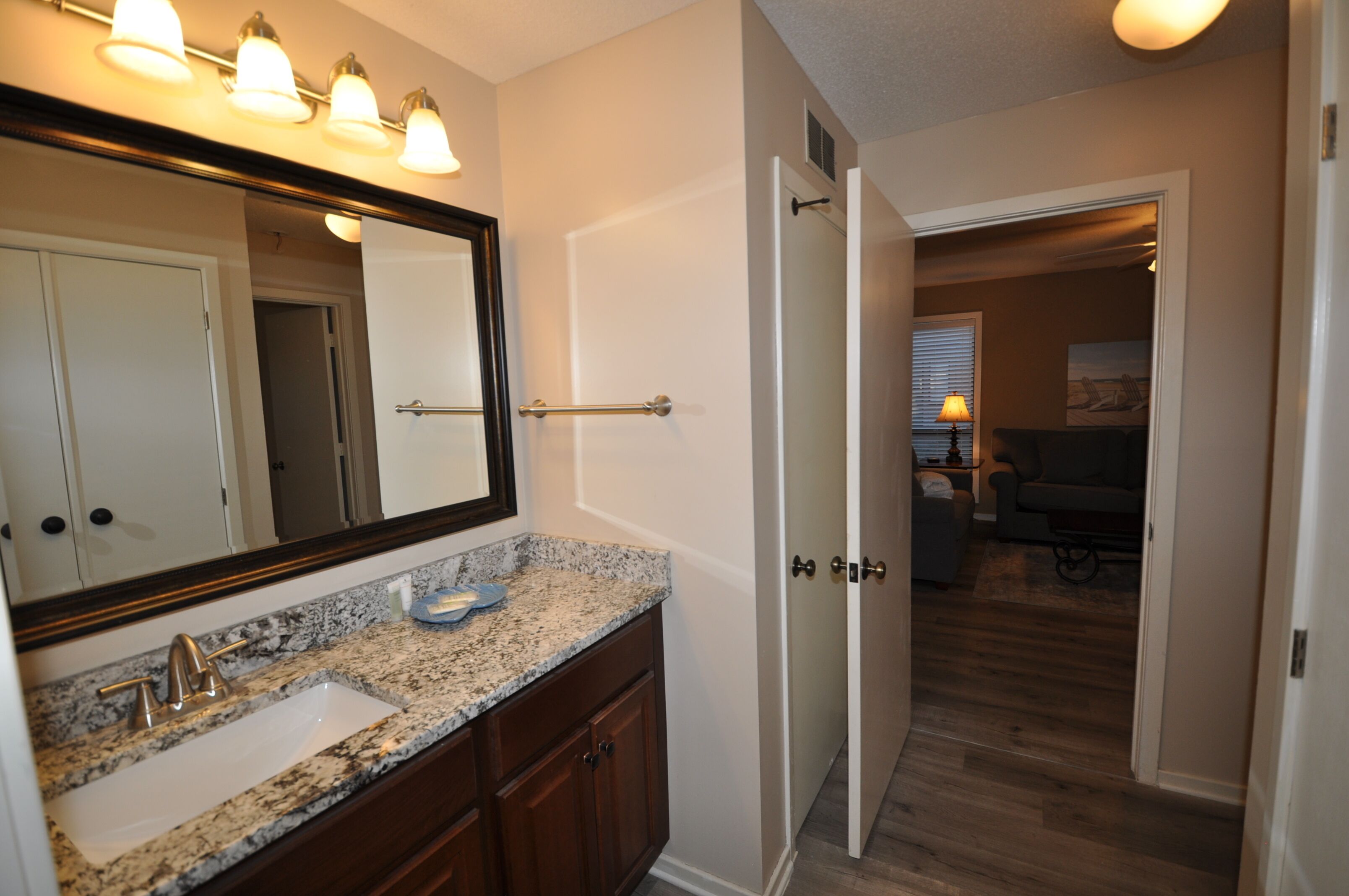 A bathroom with a granite countertop sink, a large mirror, and a towel rack.