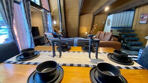 A dining area with a wooden table set for four, featuring black bowls and plates. - Cozy family friendly cabin  (Truckee)