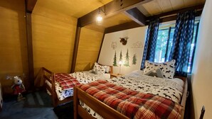 A cozy room with two wooden beds, a plush reindeer toy, and a window with patterned curtains. - Cozy family friendly cabin  (Truckee)