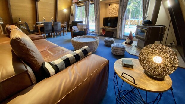 A cozy living room with a leather sofa, a round table with a woven lamp, and a television in the background. - Cozy family friendly cabin  (Truckee)