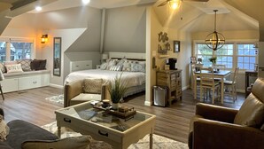 Une chambre spacieuse de style loft, dotée d’un grand lit, d’un ventilateur de plafond et d’un coin repas agrémenté d’un lustre.