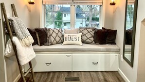 Un coin salon confortable avec un banc, des coussins et une serviette posés sur une échelle en bois.