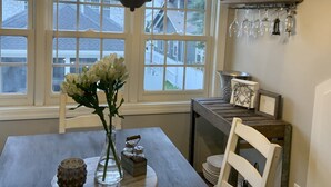 Un coin repas avec une table en bois foncé, un lustre, des chaises blanches et un vase rempli de fleurs.