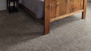 Un dormitorio con cama de madera, mesita de noche, lámpara, ventilador de techo, ventana con persianas y un cuadro en la pared.