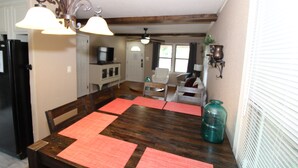 A dining area with a wooden table, red placemats, and a ceiling fan. - Right across street from Expo Center, Fenced Yard (Tulsa)