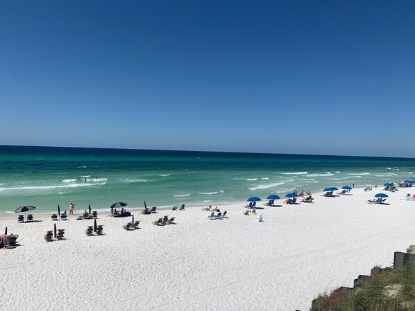 Enjoy a serene beach experience with comfortable seating and umbrellas on the pristine shore.