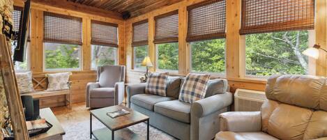 Un interior de cabaña acogedor, con un sofá, un sillón y una mesita.
