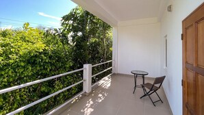 Ein Balkon mit kleinem Tisch und Stuhl, umgeben von üppiger Bepflanzung.
