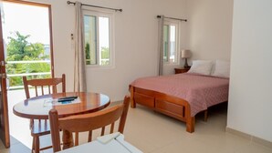Ein Schlafzimmer mit Bett, Tisch, Stühlen und einem Balkon.