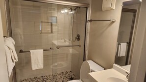 Une salle de bain moderne avec une douche à parois de verre, des toilettes blanches et un lavabo avec un miroir au-dessus.