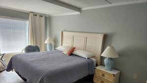 Une chambre à coucher avec un lit, des lampes de chevet, une table de chevet et une fenêtre avec des stores.