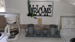 Una cocina con cafetera, letrero de bienvenida y microondas.