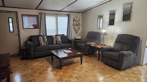 Una sala de estar amoblada con sofá, sillón, mesa de centro y lámpara.