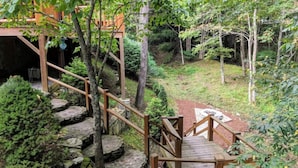 A wooden staircase leading to a covered area with a view of a forested landscape. - "Rushing Bear!"   Fully furnished two bedroom cozy cabin you want to capture!" (Maggie Valley)